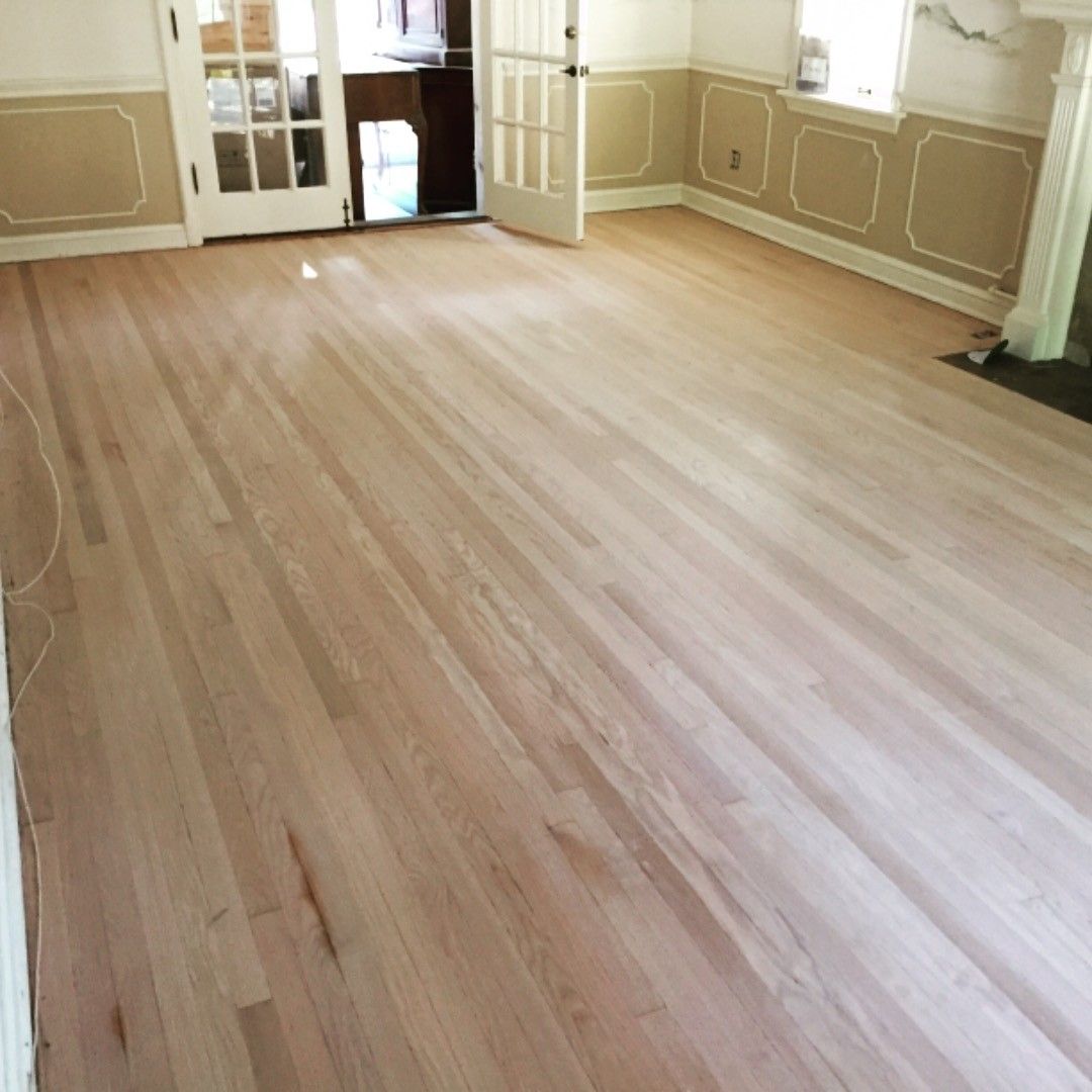Empty room with light wood flooring and cream walls, viewed toward glass-paned doors.