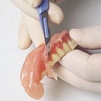 Une personne coupe une prothèse avec un scalpel.