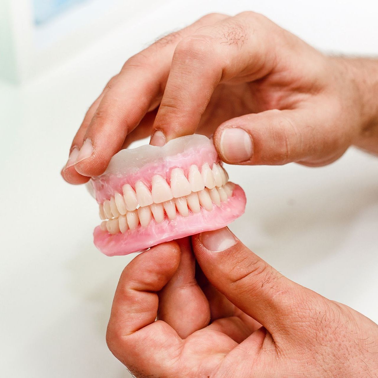 Une personne tient une fausse série de dents dans ses mains