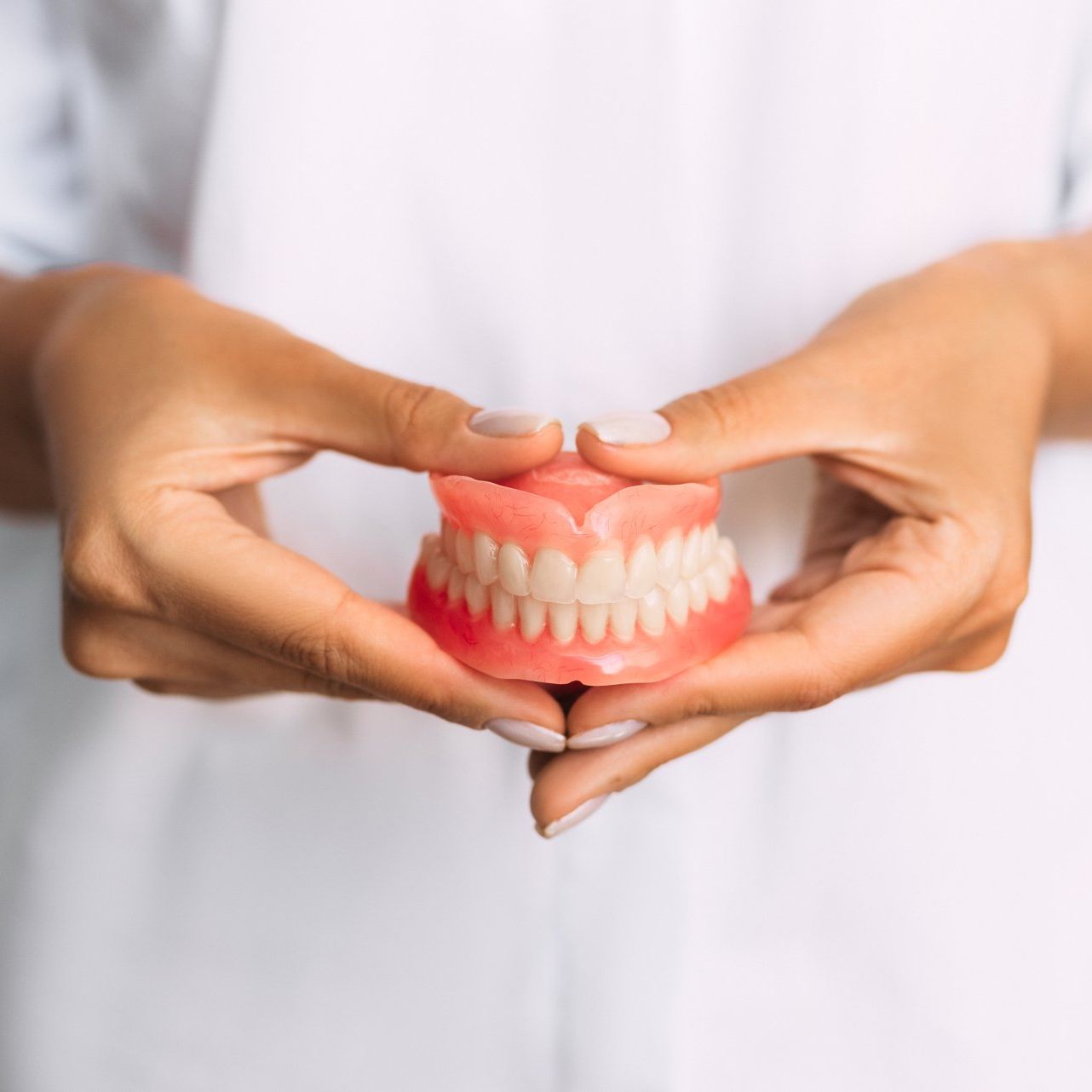 Une femme tient un modèle de dents dans ses mains.