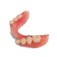 A close up of a denture with teeth on a white background.