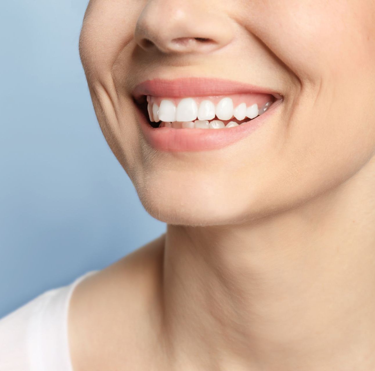 Un gros plan du sourire d'une femme avec des dents blanches et des lèvres roses.
