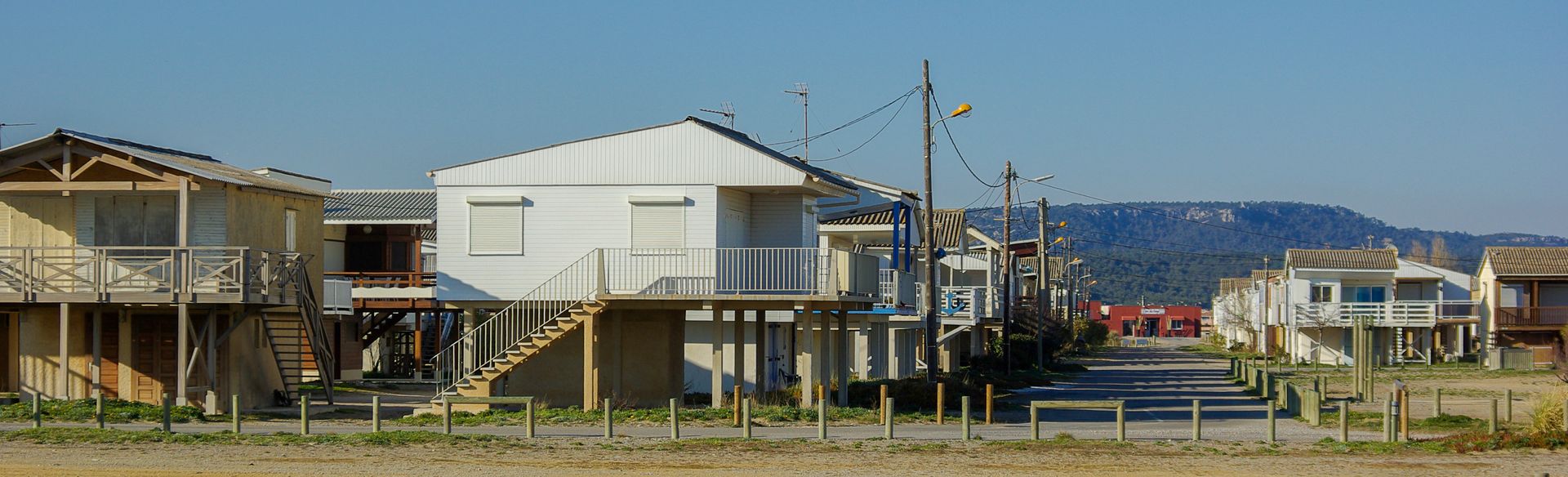 Rural coastal neighborhood with small houses and utility poles under a clear blue sky