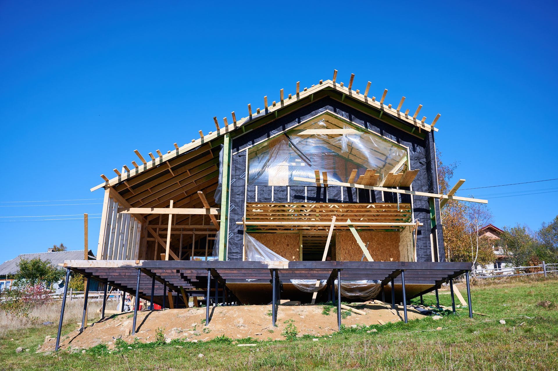 Partially built wooden house with scaffolding under a clear blue sky