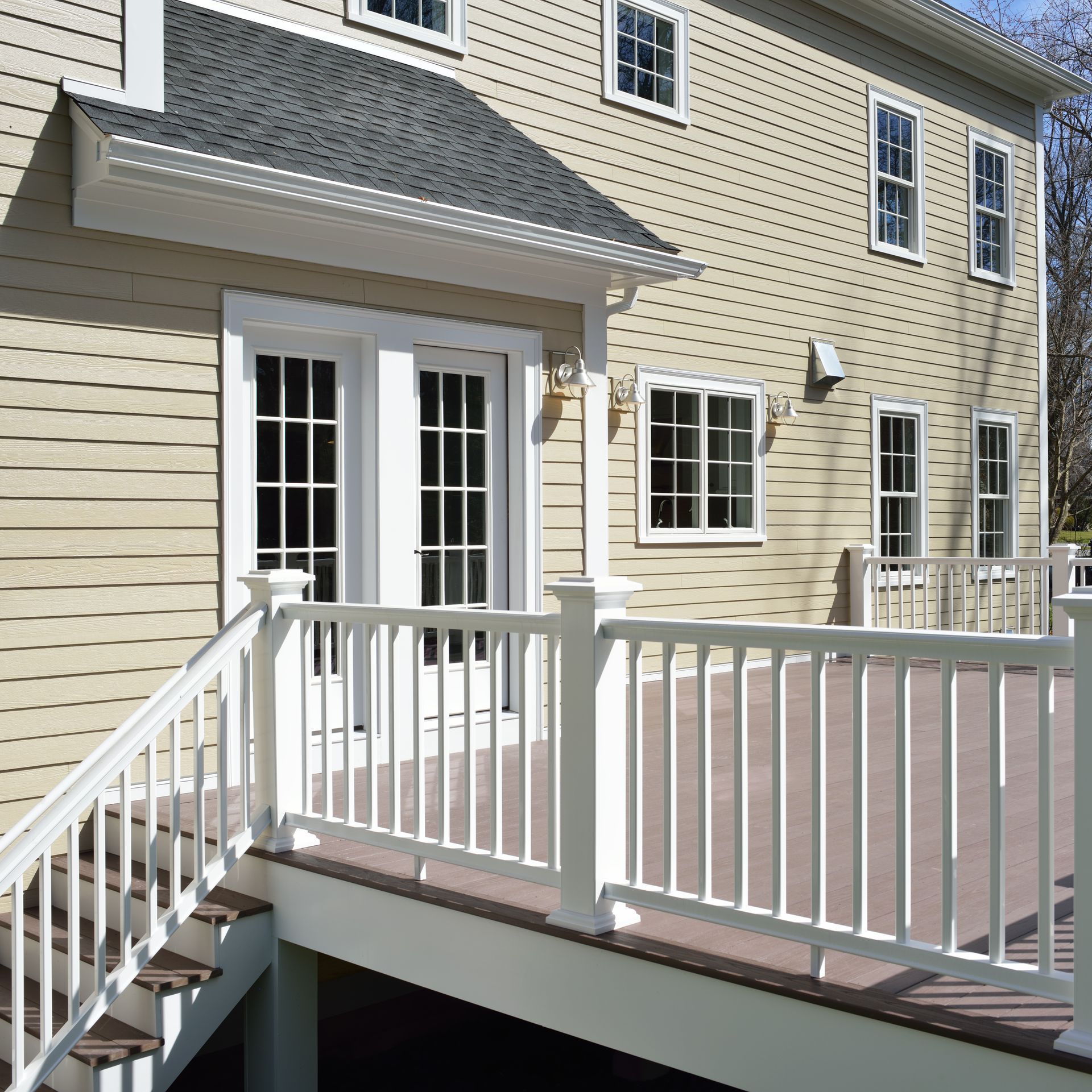 Beige house exterior with white-railed deck and double French doors.