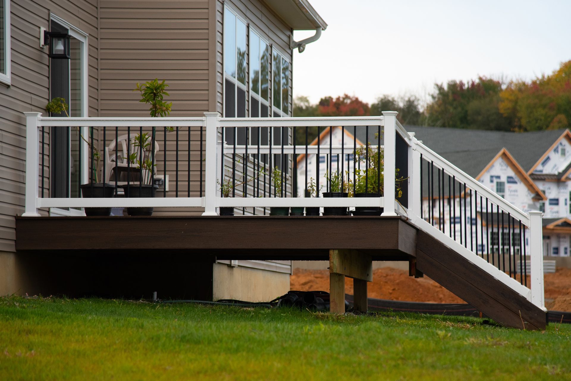 Back deck with white railing and stairs beside a gray house overlooking a green lawn