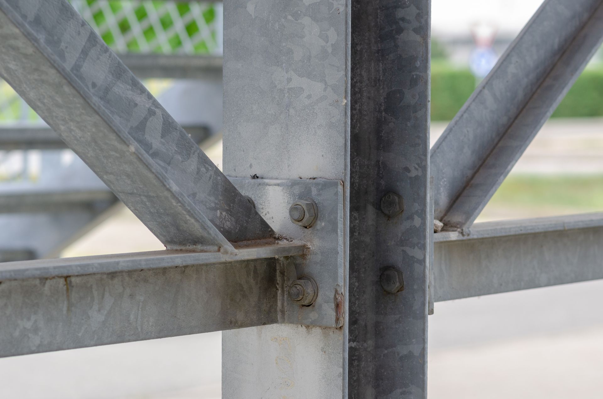 Close-up of rusted metal bridge truss beams and bolts against a blurred background
