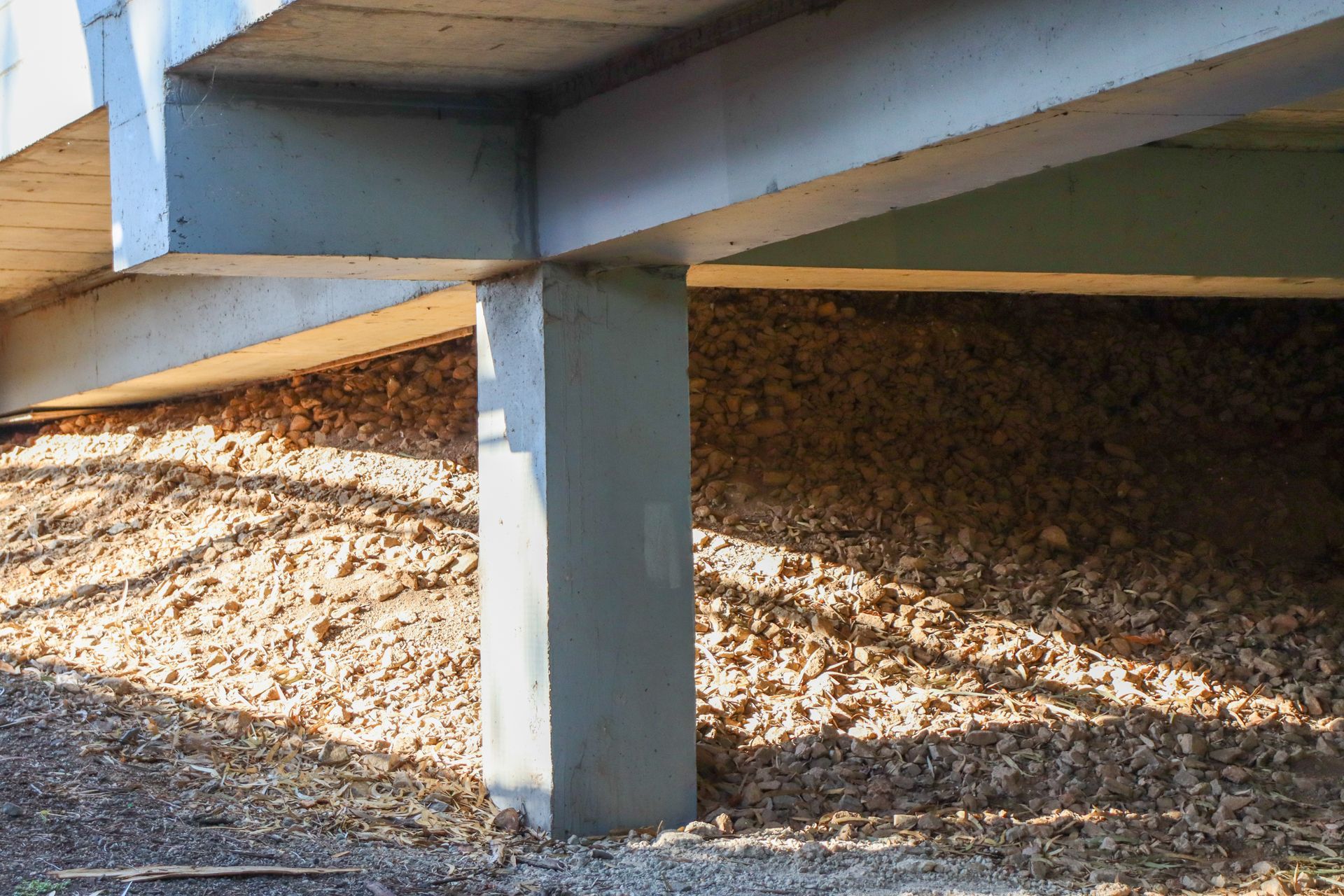 Concrete bridge support pillar over gravel in bright sunlight