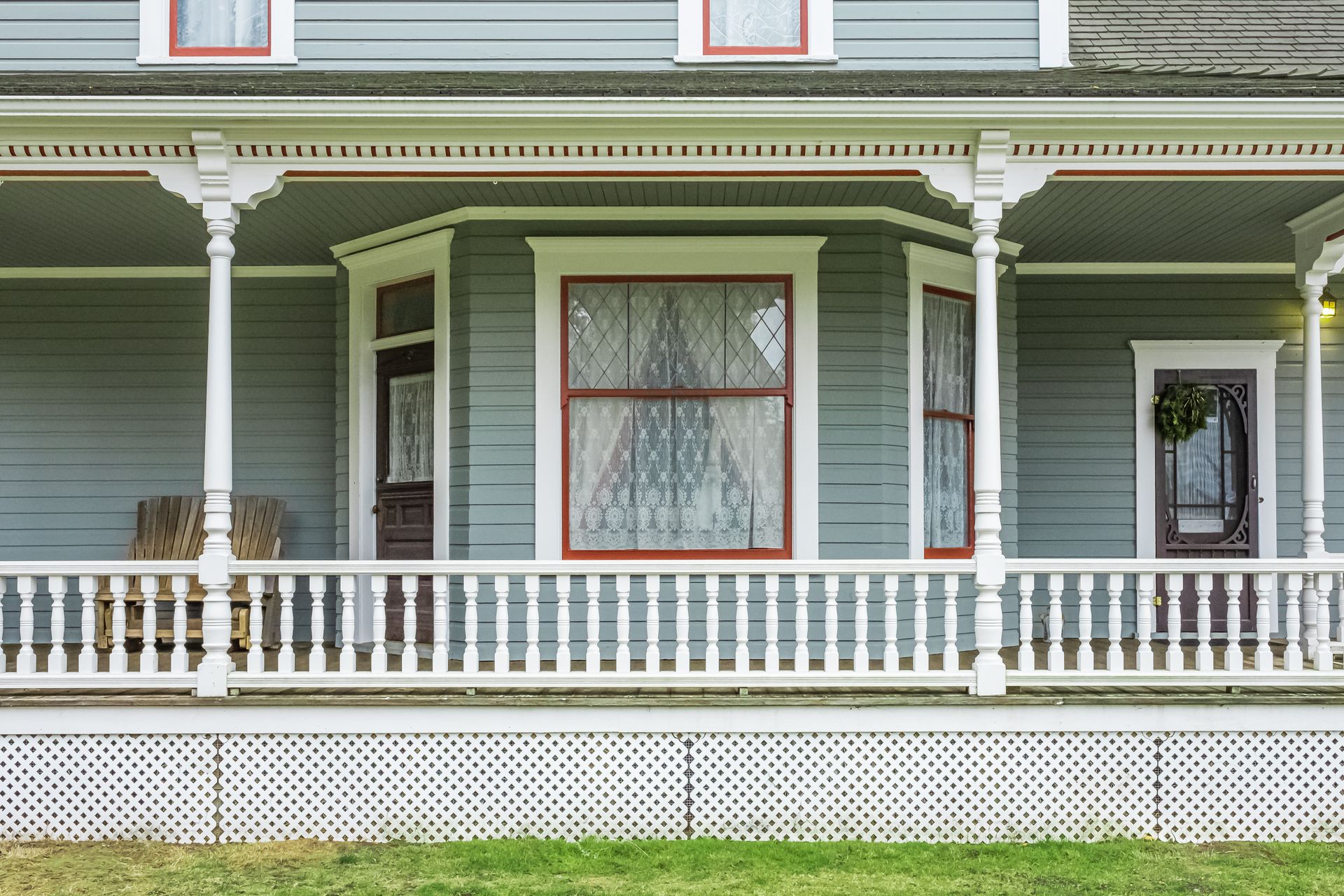 Victorian house porch with green siding, white trim, and decorative railings