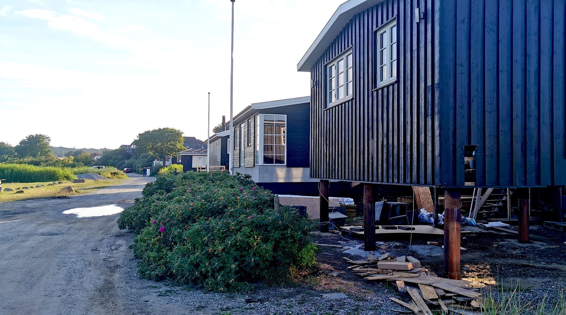 Blue stilted cabins beside a gravel road in a sunny rural area
