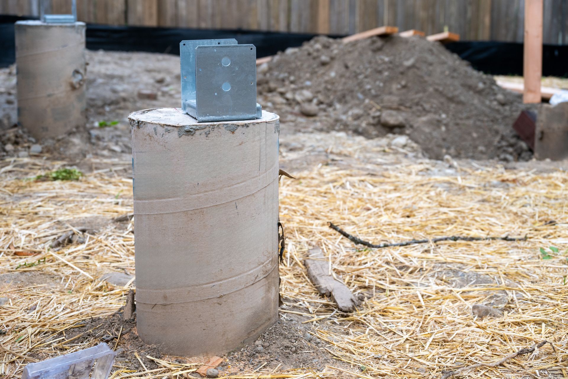 Concrete pillar with a metal bracket in a straw-covered construction site