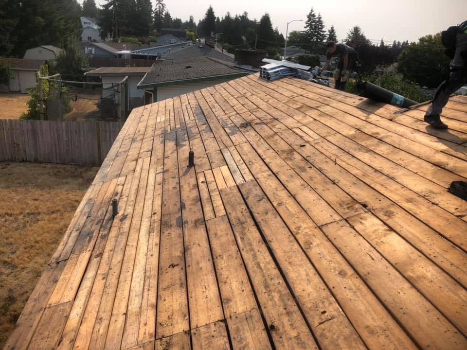 Wooden roof under construction with worker, overlooking suburban homes and trees