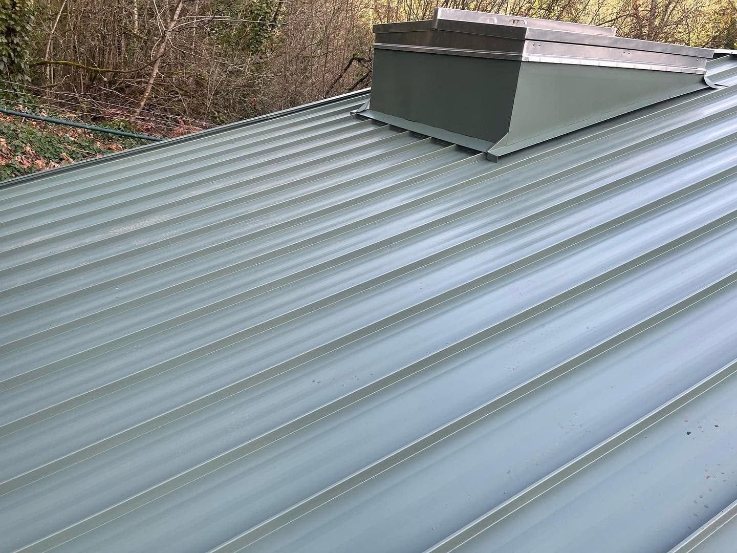 Gray metal roof with raised seams and a rooftop vent, viewed from above