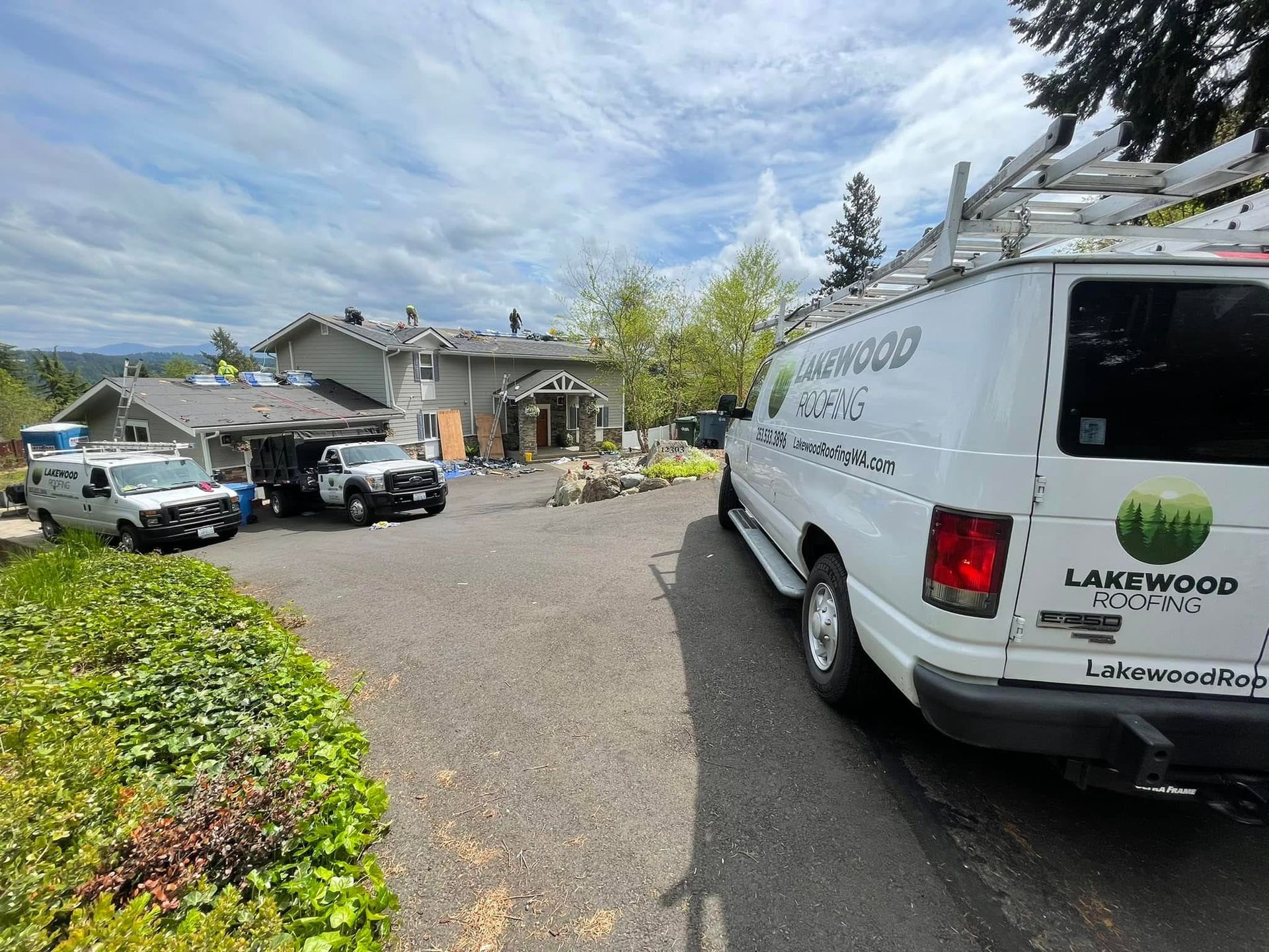 Parking lot at a stone building, with a white service van in the foreground and cars lined up nearby.