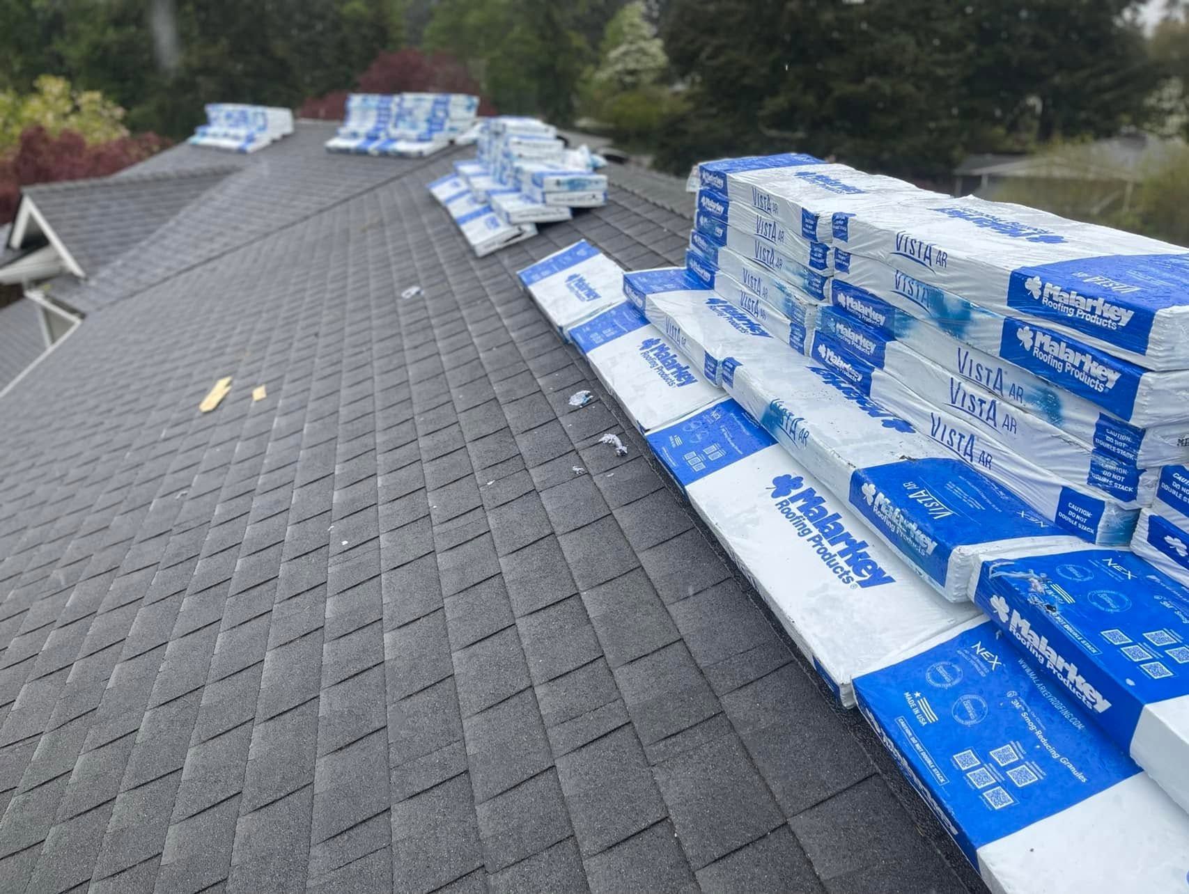 Roof under repair along a steep gray shingle roof