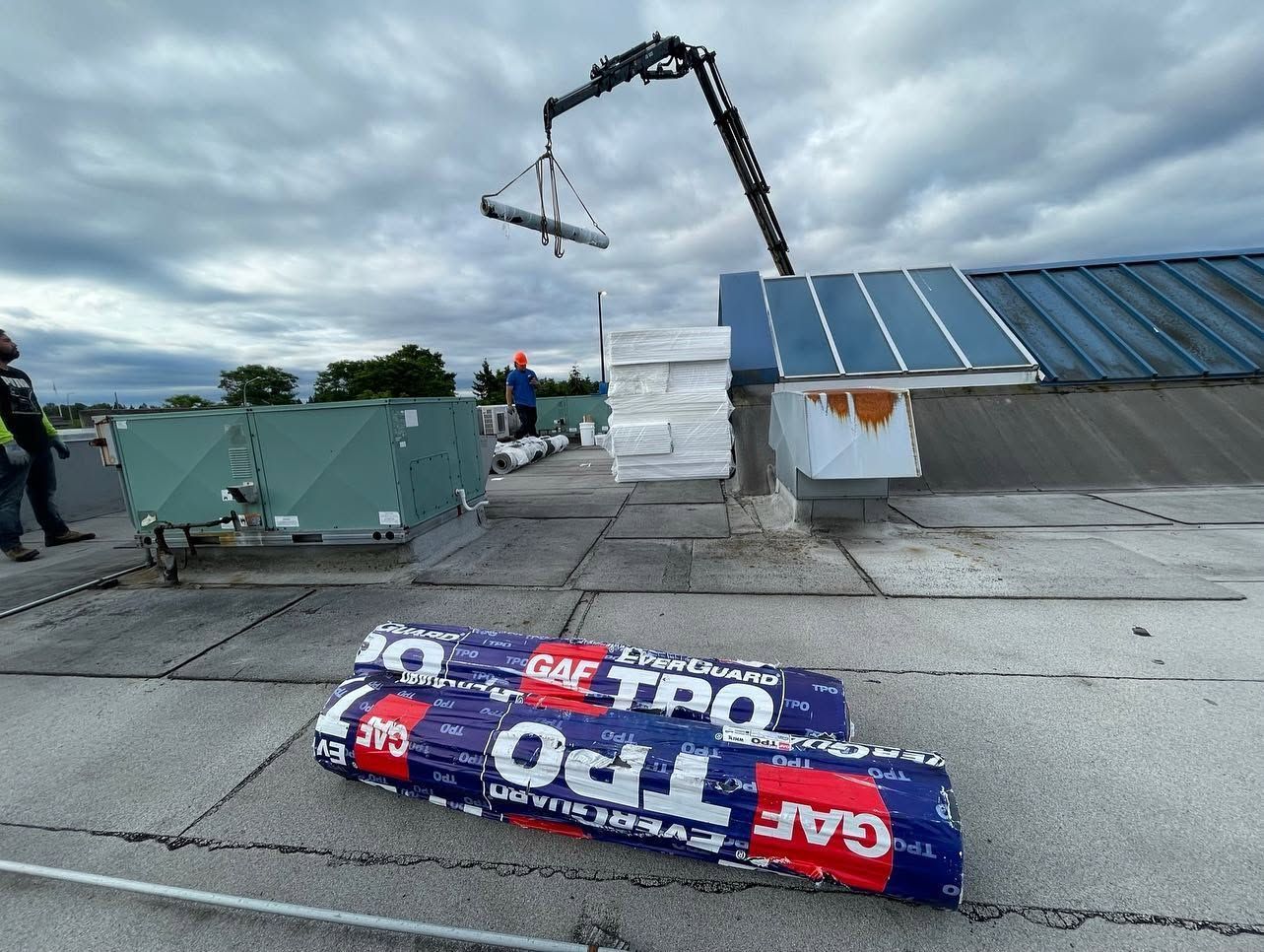 Rooftop scene with a crane lifting a white load beside solar panels and a fallen red-blue banner.