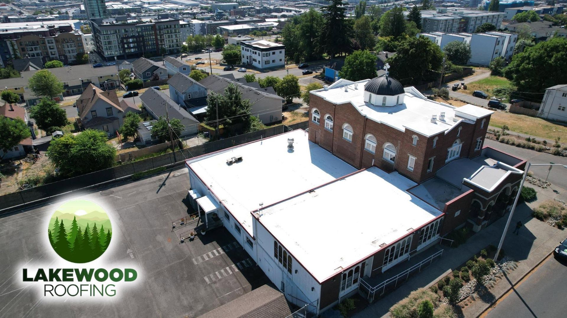 Aerial view of a flat-roof commercial building with a dome, surrounded by nearby homes and trees.