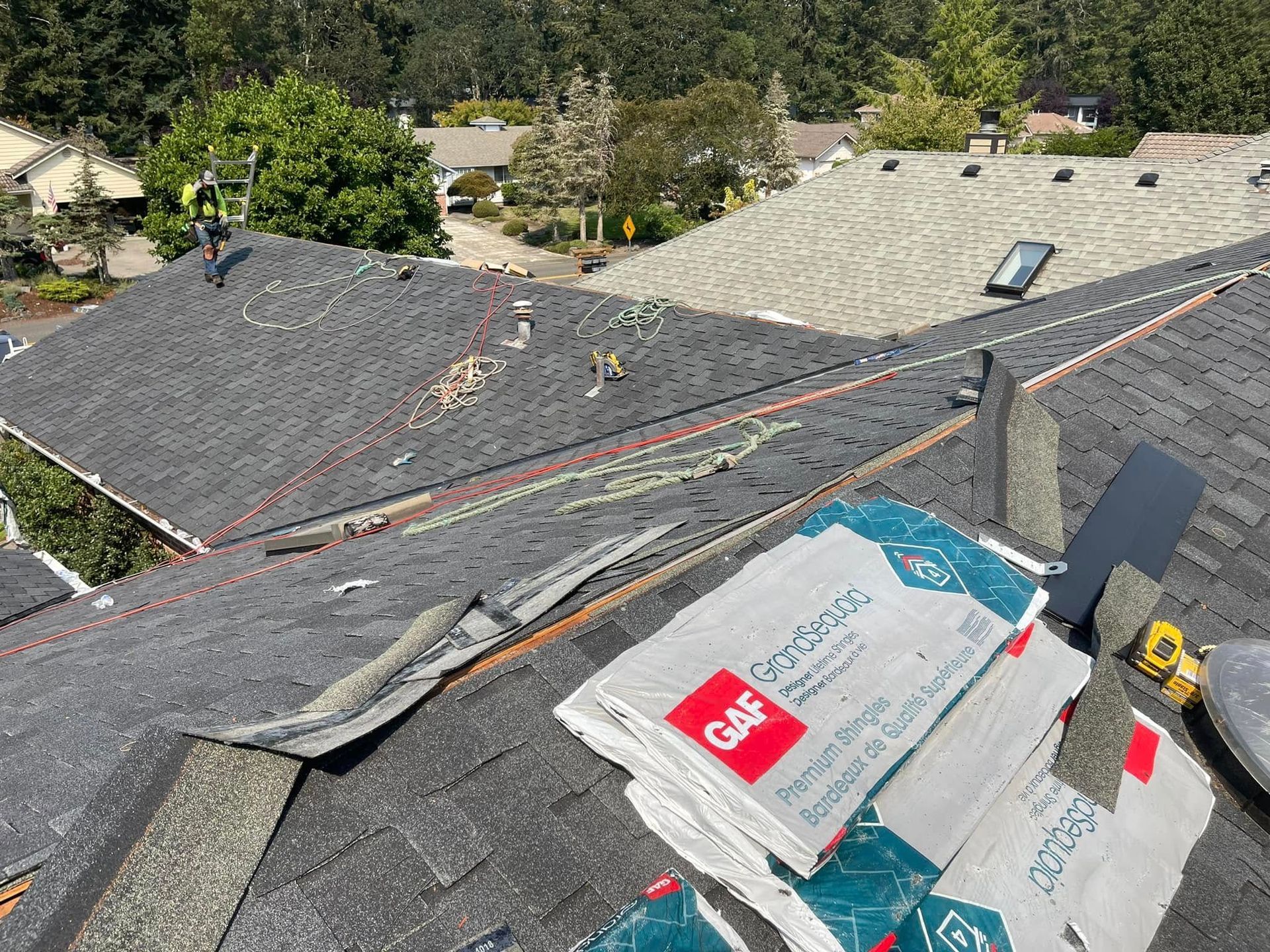 Damaged roof with torn shingles and roofing materials laid out during repair, viewed from above