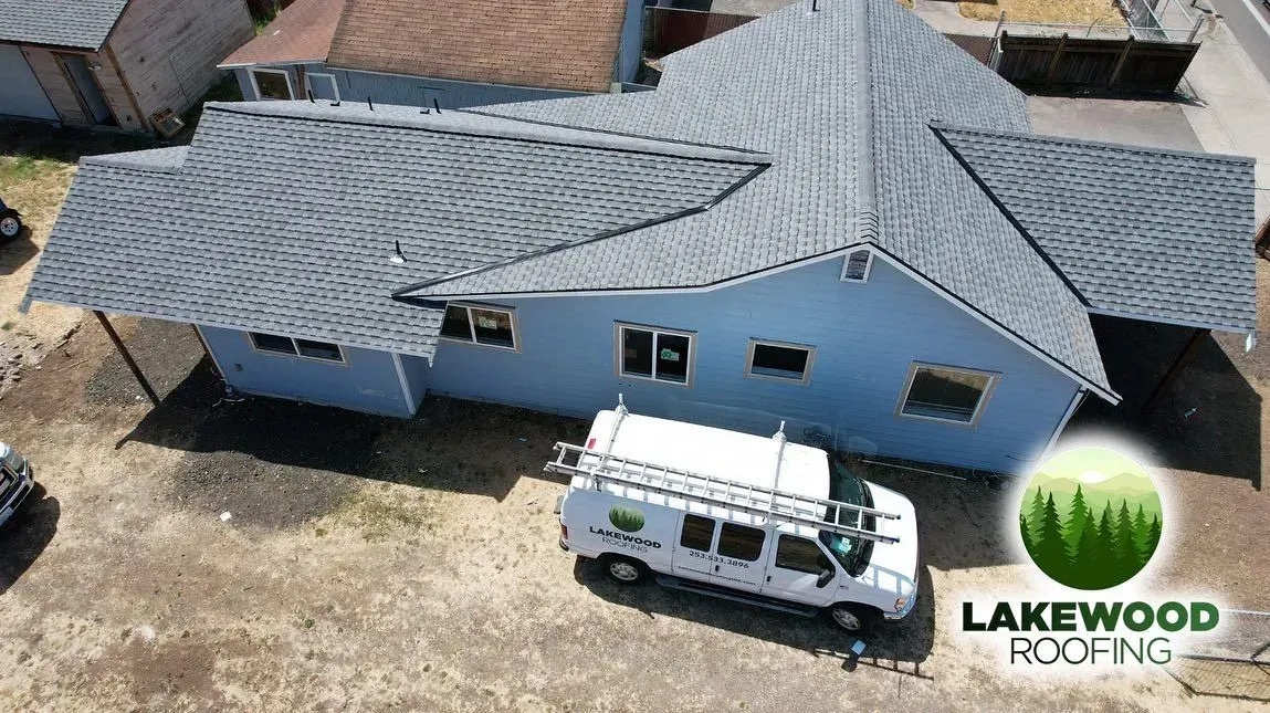 Aerial view of a roof with blue underlayment with a gray roof and a white van parked beside it.