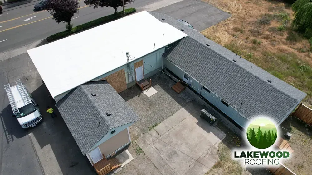 Aerial view of a single-story building with a white roof, parking area, and Lakewood Roofing logo in the corner
