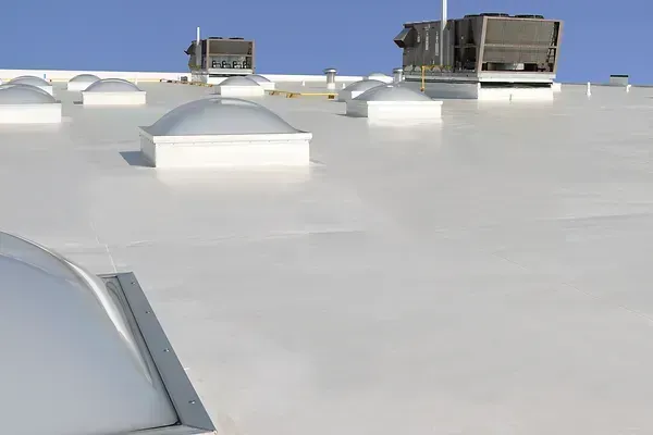 Flat white rooftop with several HVAC units under a clear blue sky.