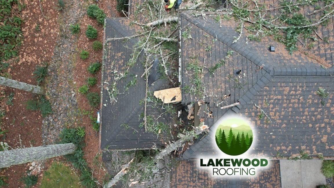 Aerial view of a storm-damaged roof with debris and a visible Lakewood Roofing logo