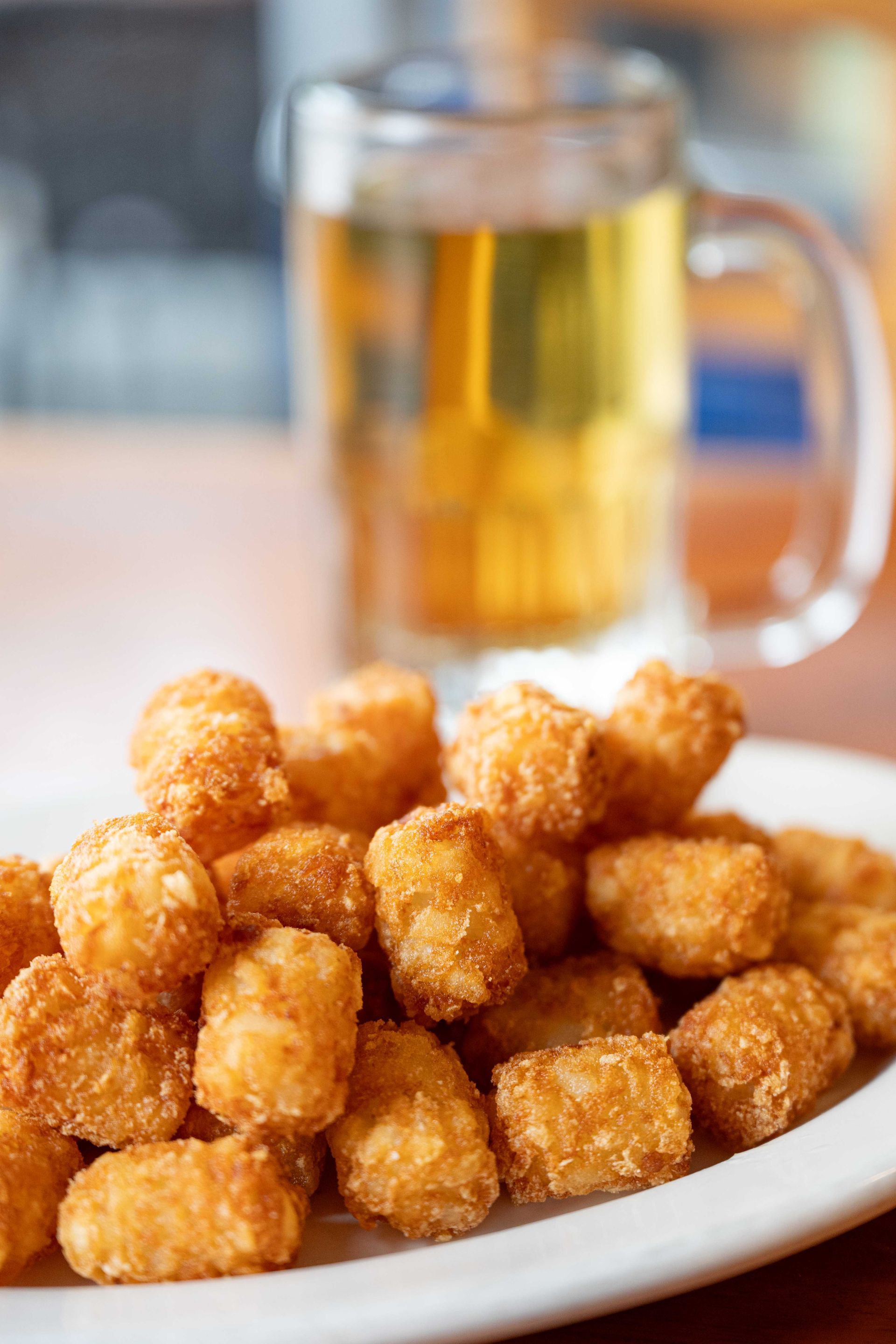 Plate of golden tater tots with a mug of beer on a table