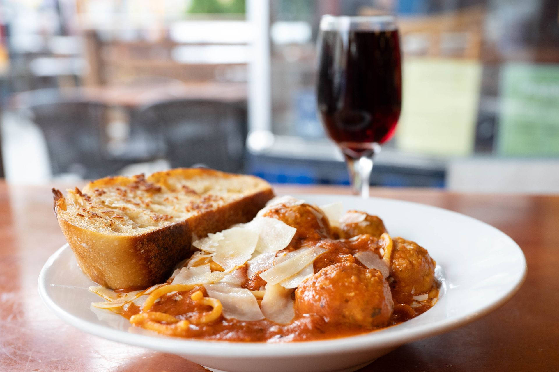 Plate of pasta with bread and a glass of red wine on a restaurant table
