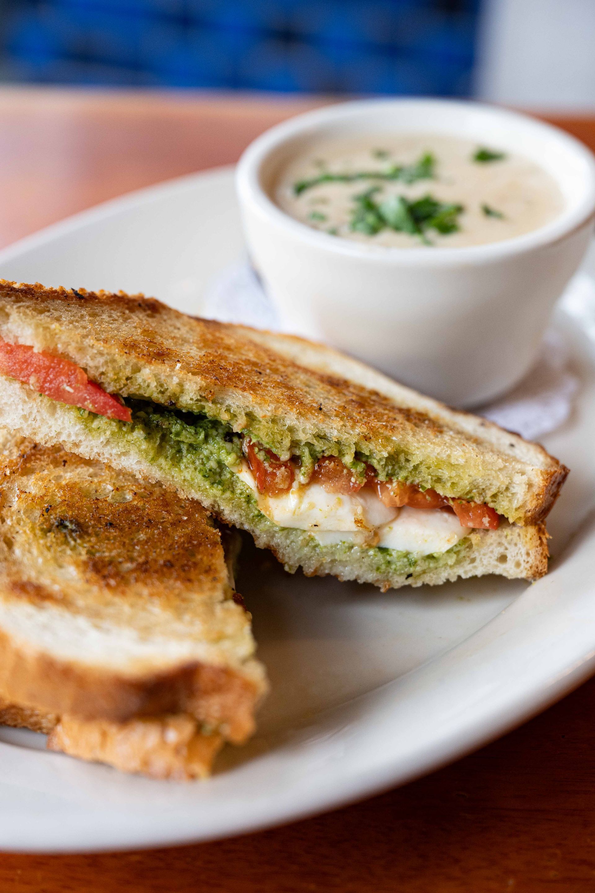 Grilled sandwich on a plate with a bowl of creamy soup, served on a table