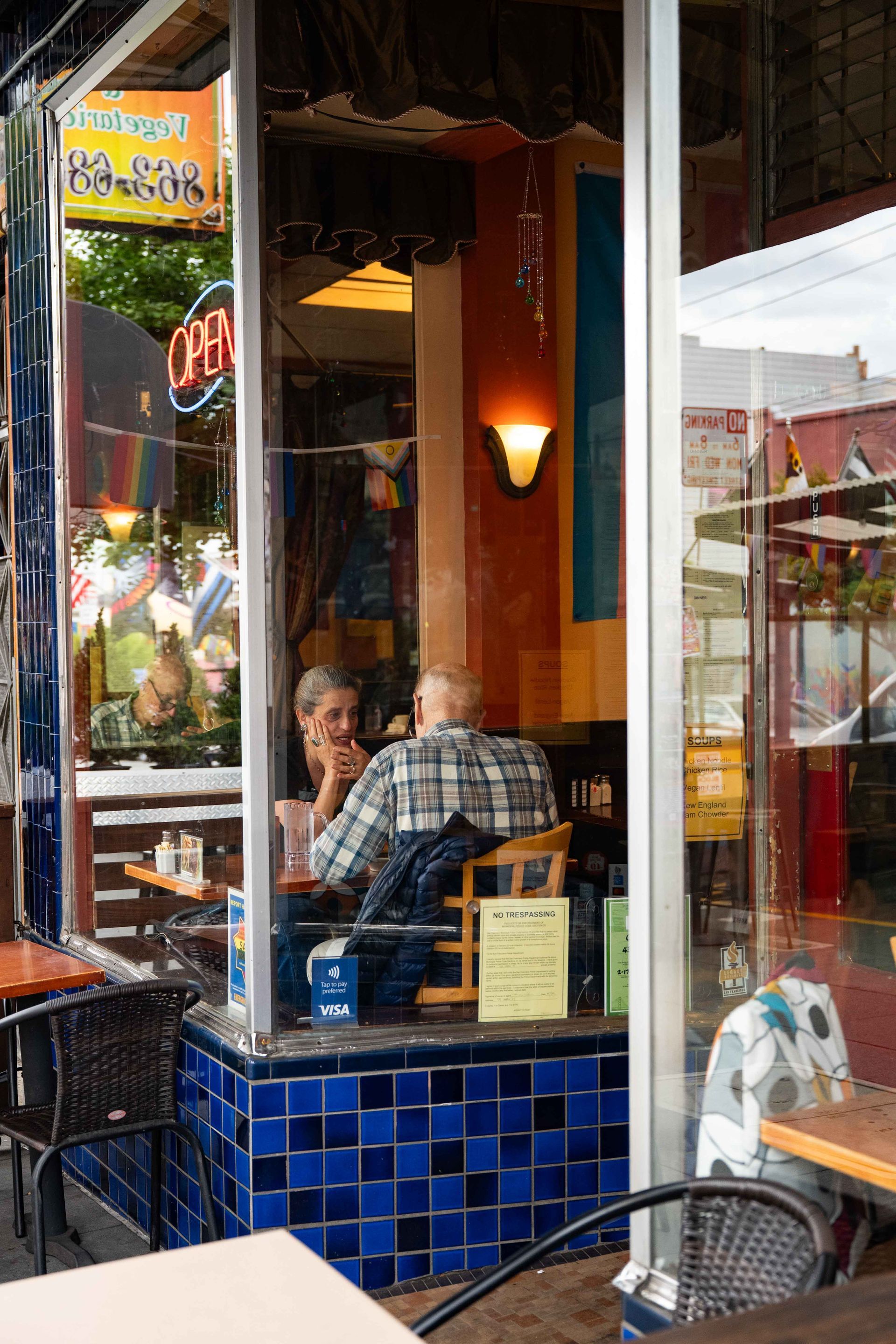 Cafe table with two people seated inside by a colorful storefront window