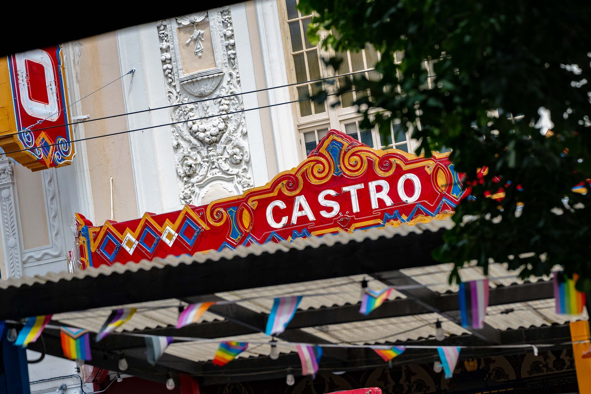 Colorful “Castro” marquee sign on a street facade with festive bunting and trees nearby