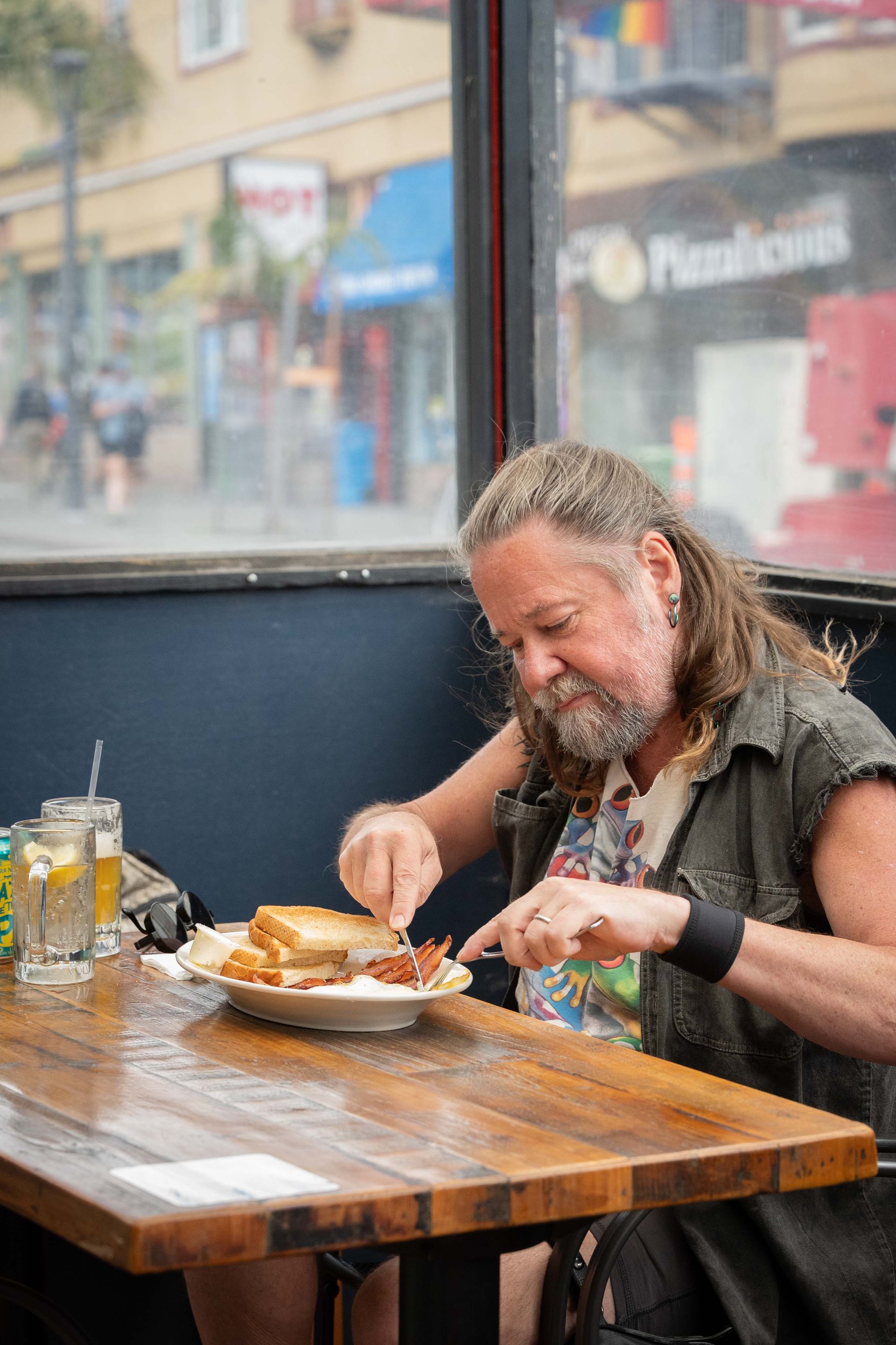 Man eating a meal at a wooden table by a window in a café