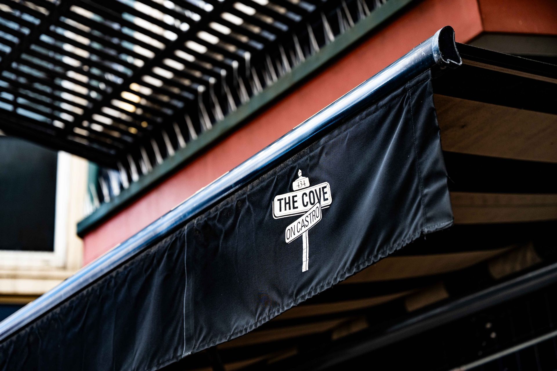 Black awning with “THE COVE” logo under a slatted overhang on a building