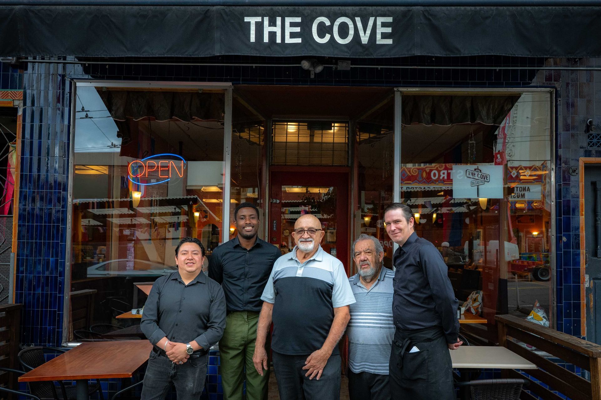 Five people standing outside The Cove storefront at dusk, smiling in front of the entrance.