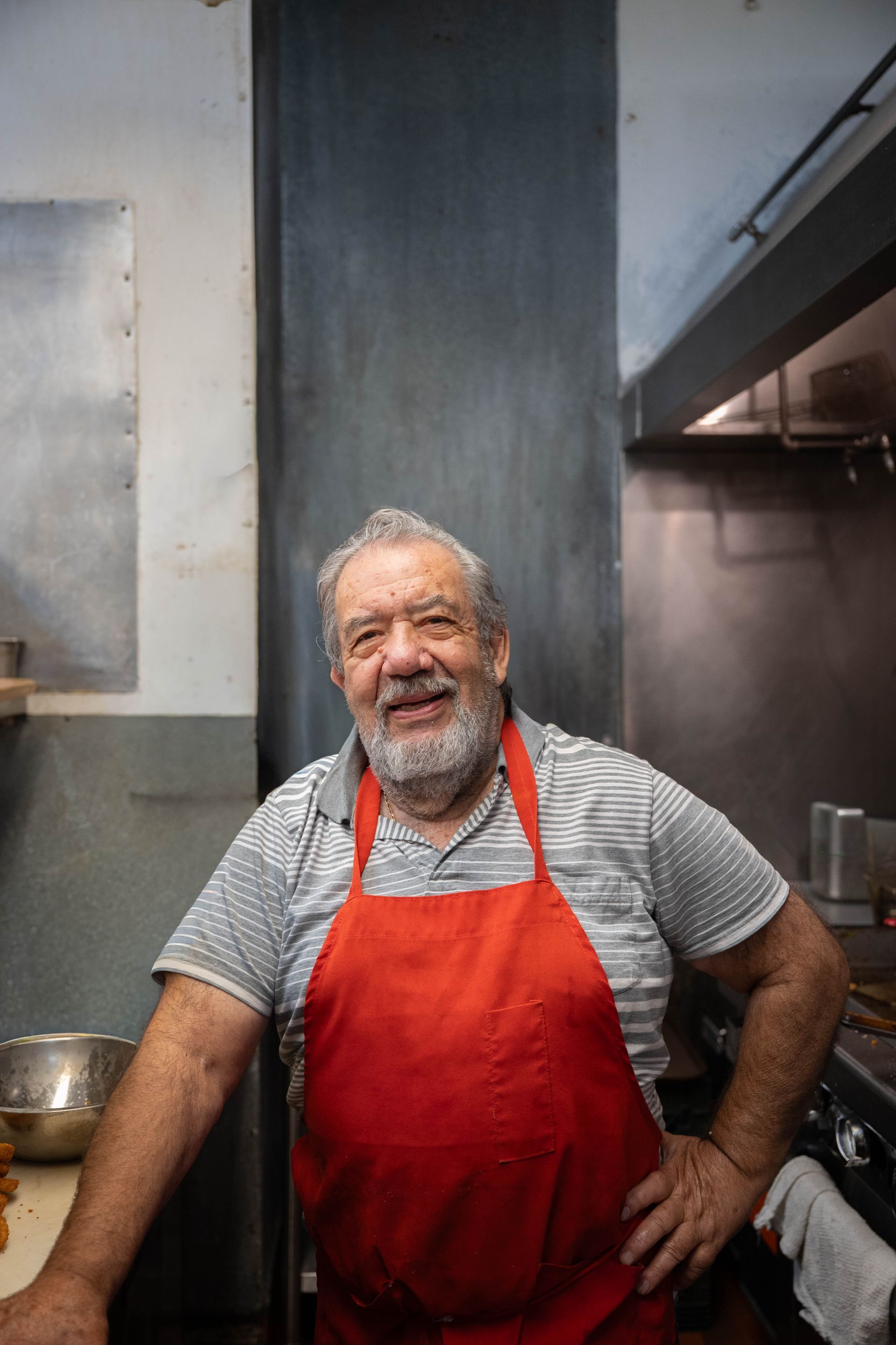 Smiling chef in a red apron standing in a commercial kitchen