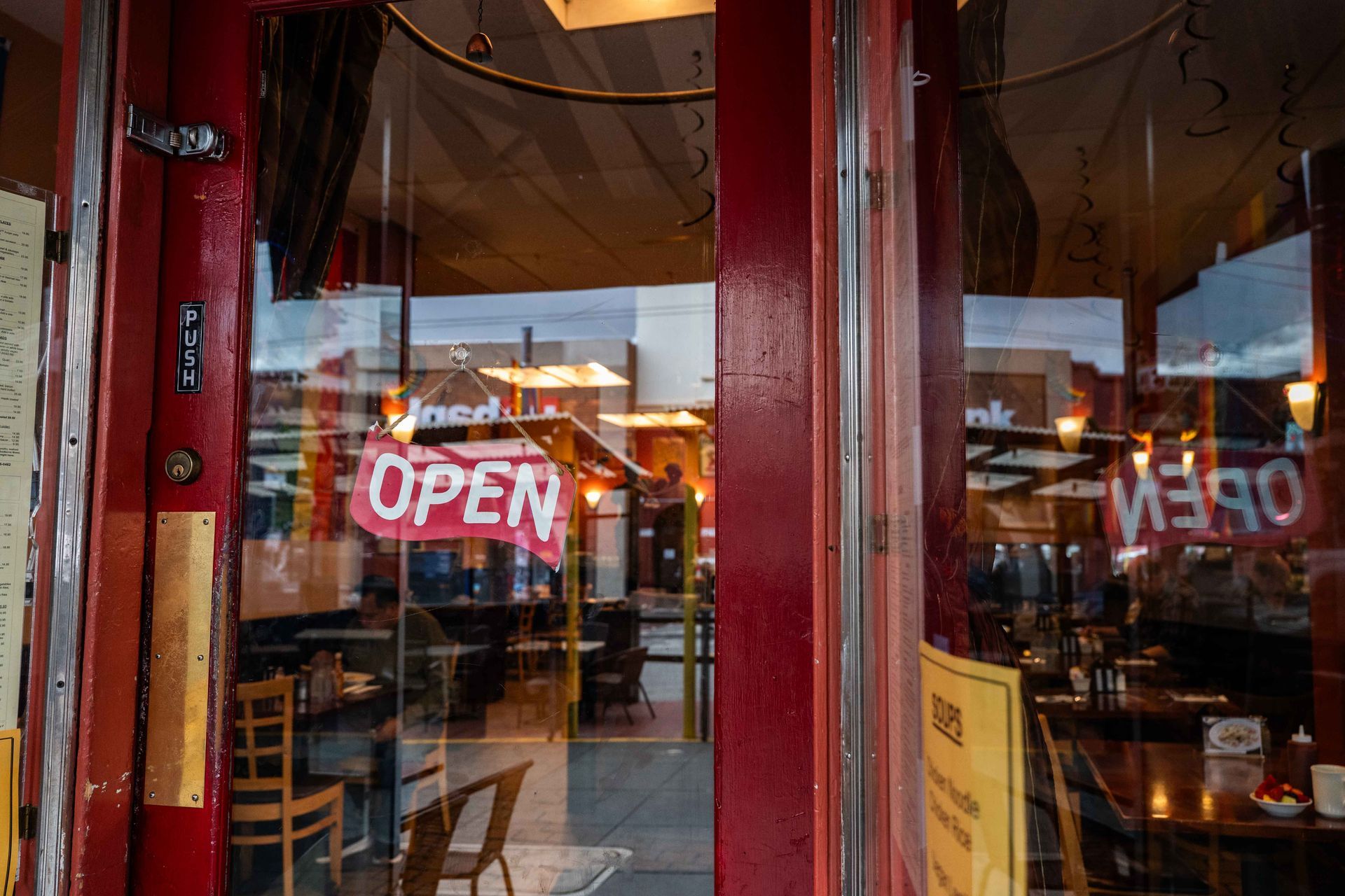 Restaurant window with red neon OPEN sign and reflections of tables inside