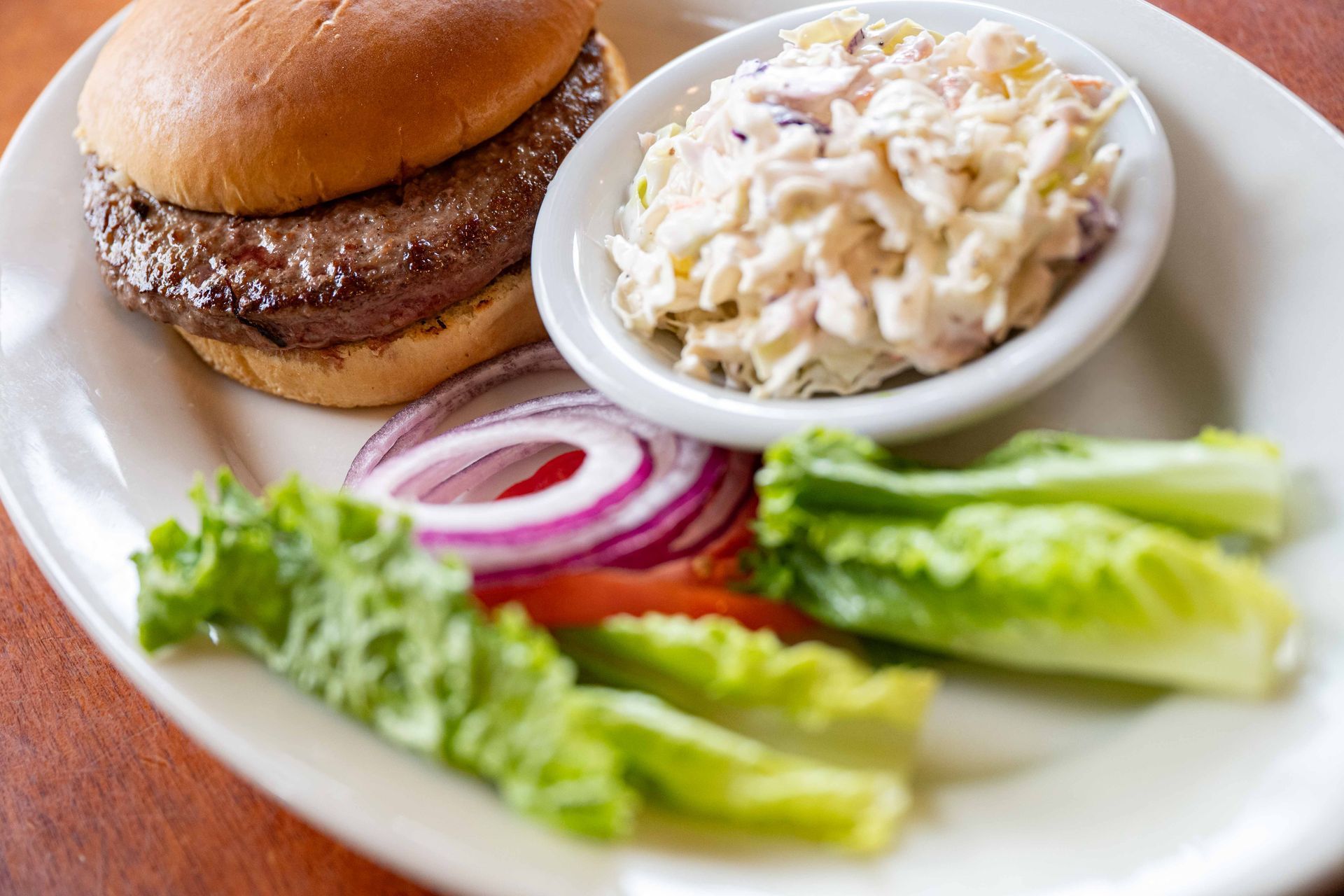 Burger with rice, lettuce, and red onion slices on a white plate