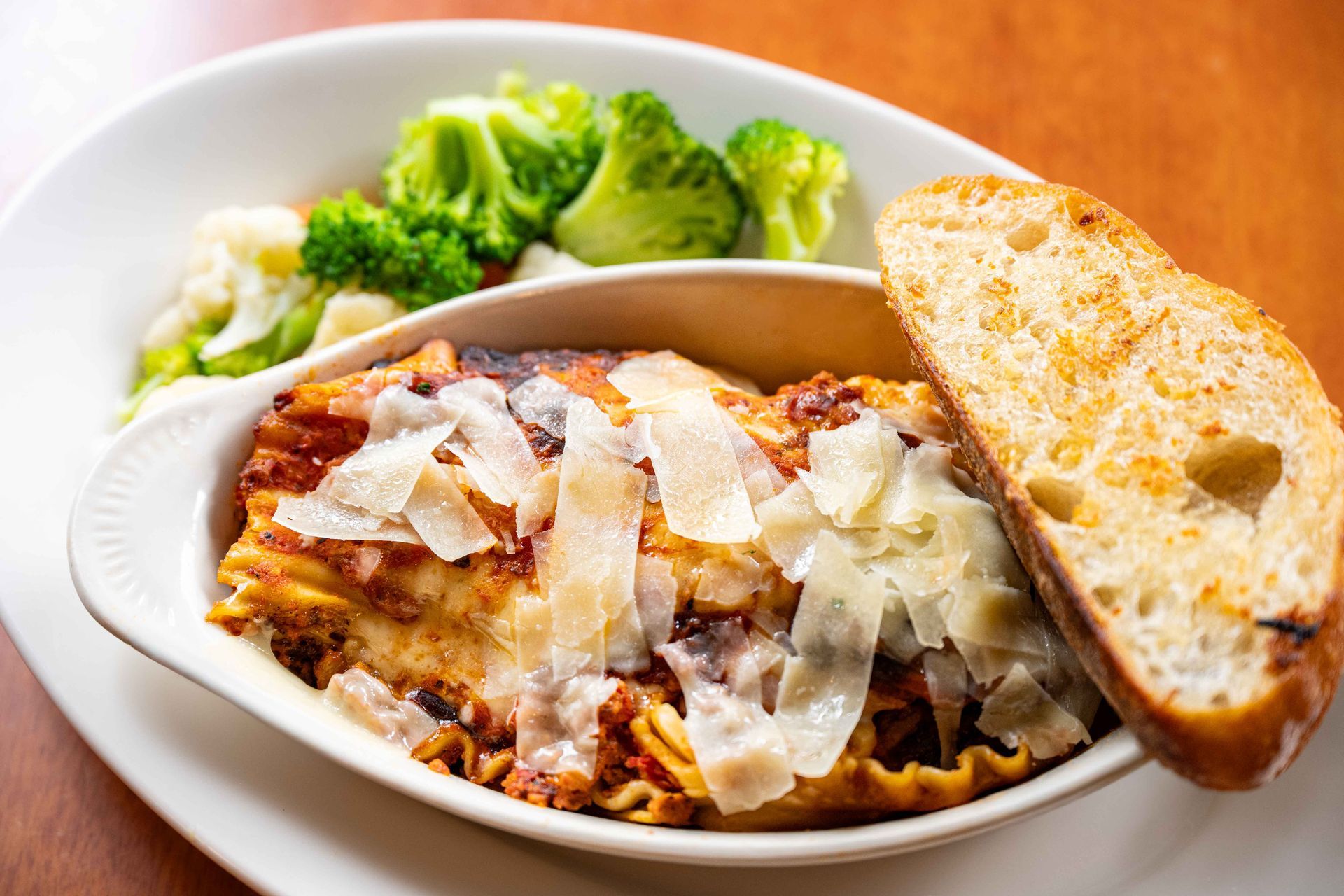 Pasta with melted cheese in a bowl, served with broccoli and a slice of bread
