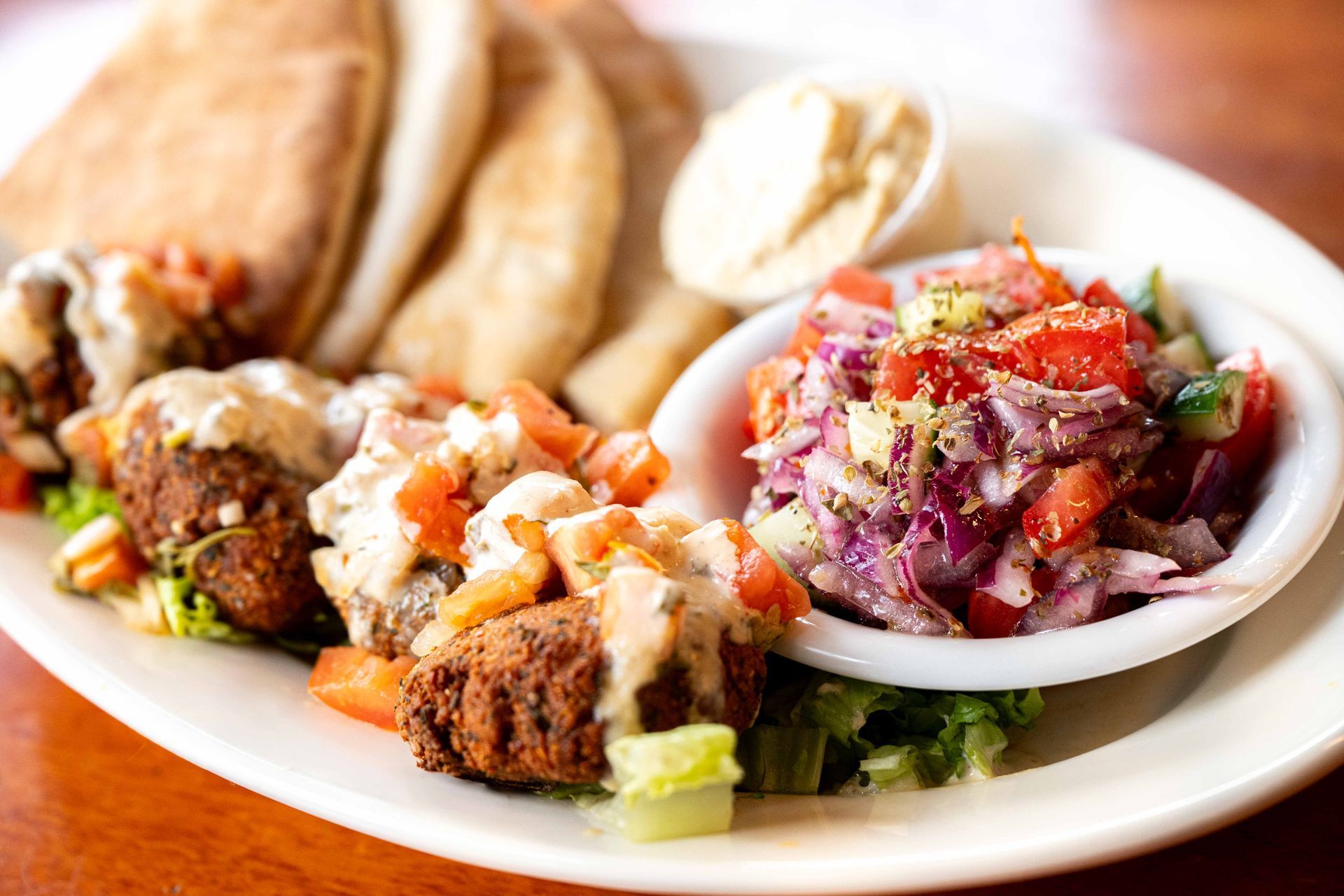 Plate of falafel, pita bread, and chopped salad with red onions and tomatoes