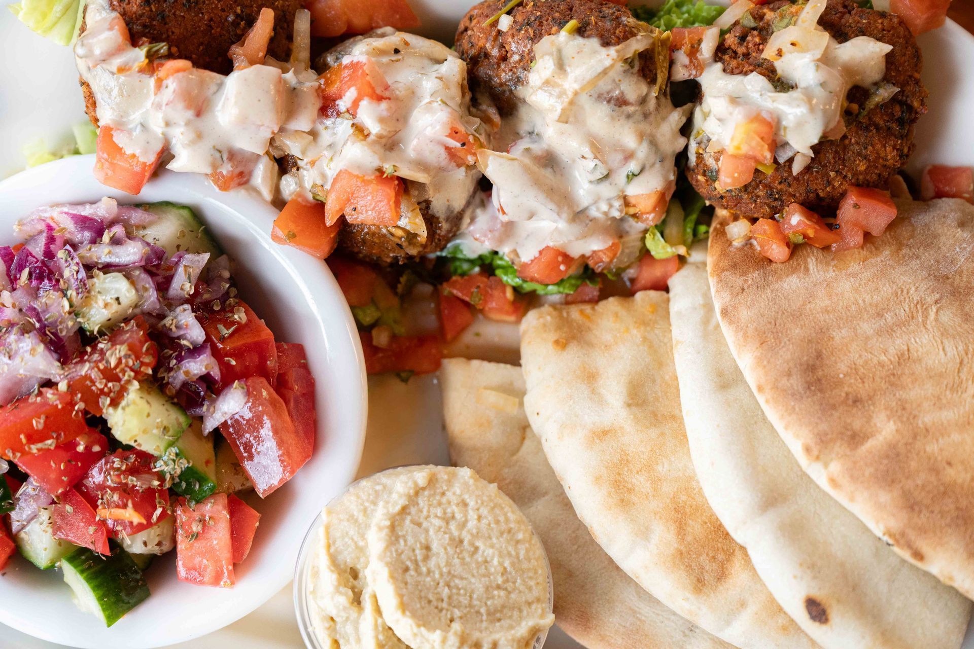 Plate of Mediterranean food with stuffed wraps, pita, grilled meat, and a fresh salad