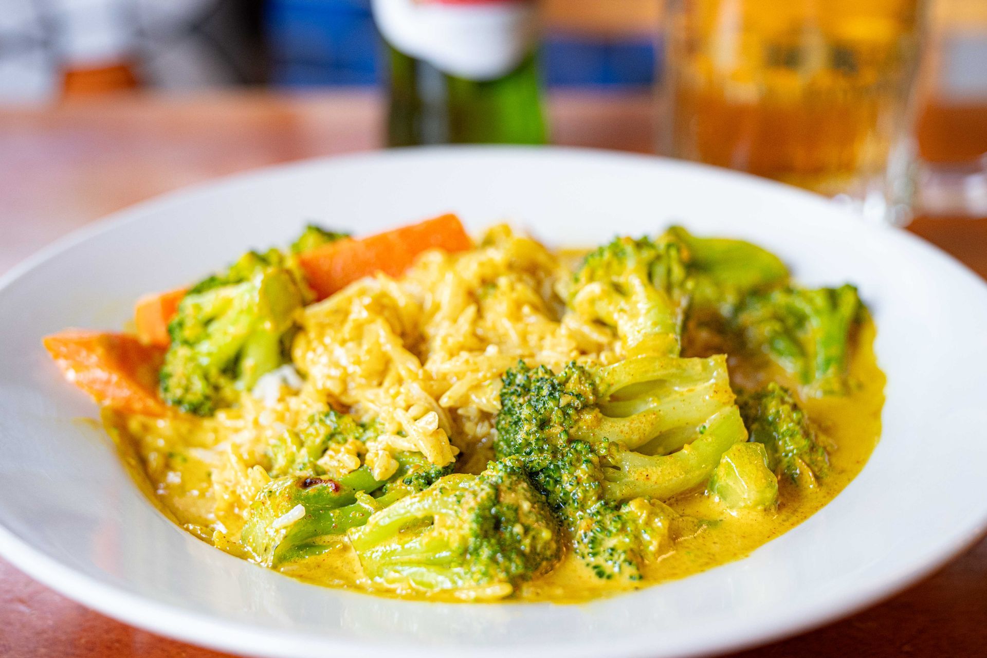 Plate of broccoli, carrots, and rice in a creamy yellow sauce on a table