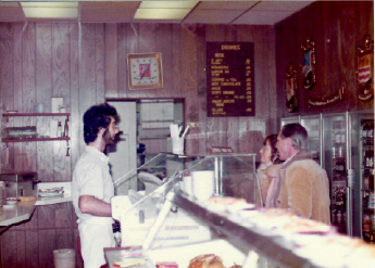 People standing at a vintage diner counter with wood-paneled walls and a menu board in the background