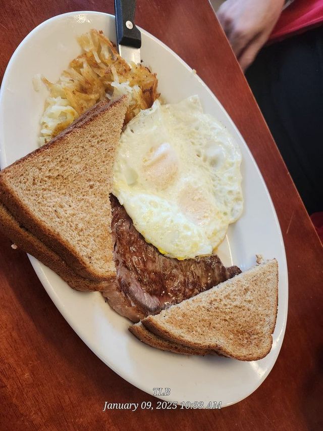 Breakfast plate with toast, fried egg, hash browns, and a sausage patty on a white plate