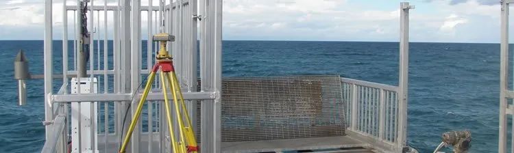 A tripod is sitting on top of a metal structure next to the ocean.
