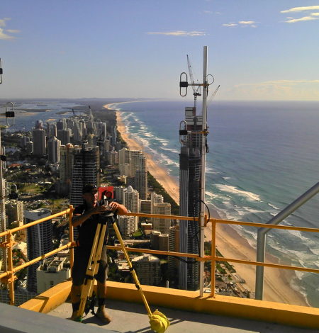 A man stands on top of a building overlooking a city and ocean