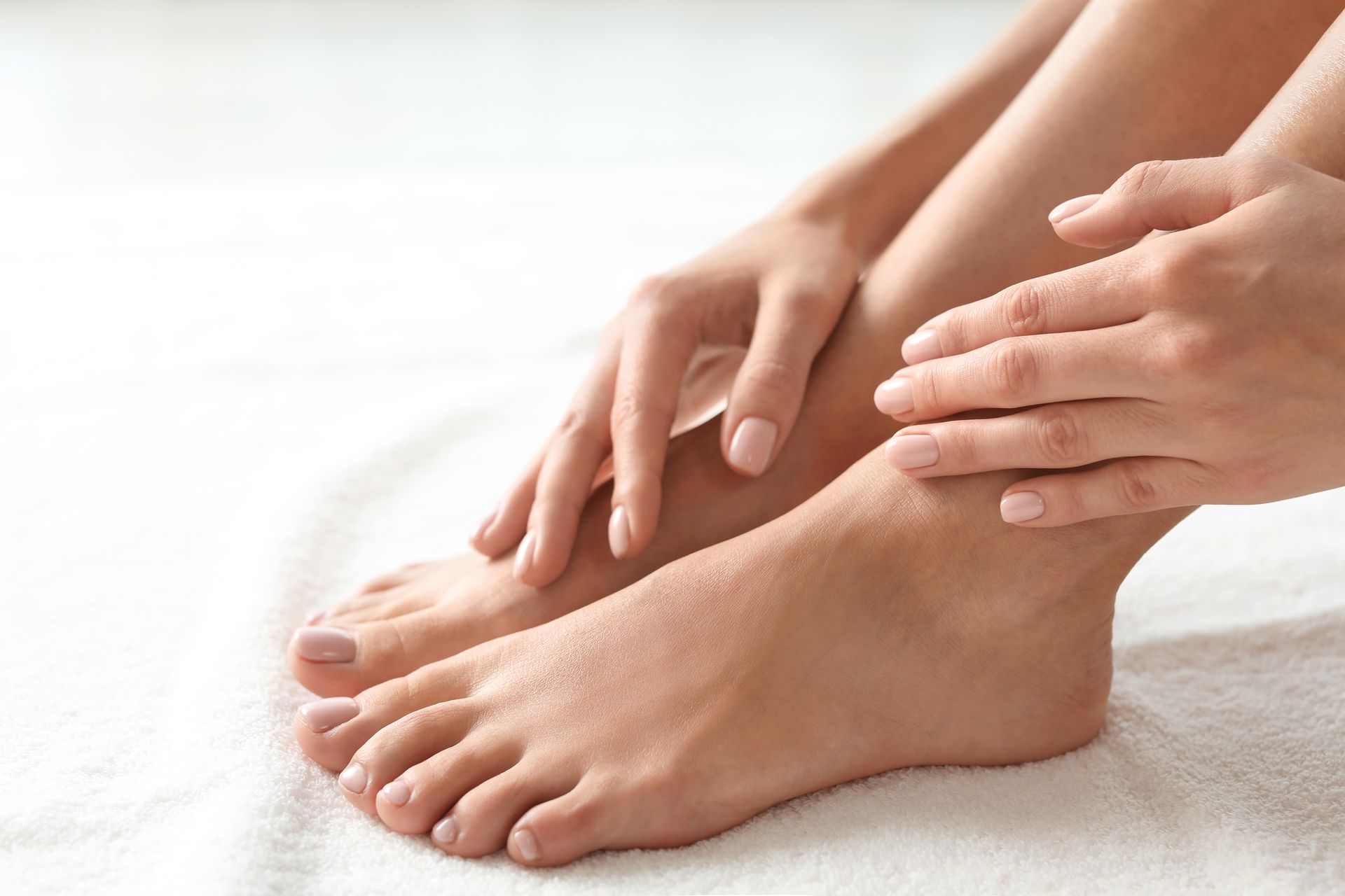 Une femme touche ses pieds sur une serviette blanche