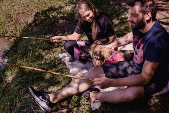 Um homem e uma mulher estão sentados no chão com um cachorro.