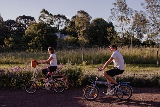 Um homem e uma mulher andam de bicicleta em uma estrada de terra.