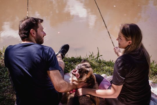 Um homem e uma mulher estão sentados em um cobertor com um cachorro.
