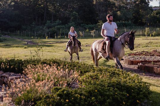 Um homem e uma mulher estão andando a cavalo em um campo.